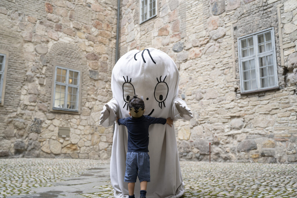 Barn med kungakrona kramar Lilla spöket laban på Örebro slotts borggård.